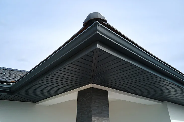 Dark seamless gutters and matching soffit on a modern home corner